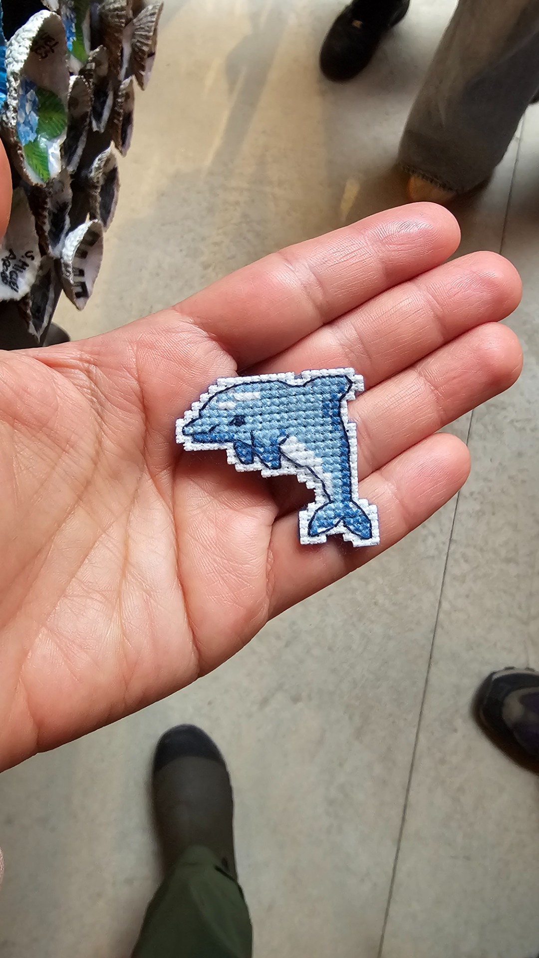 February 2026. Finding wholesome souvenirs at an Azores gift shop: a dolphin magnet, handcrafted in cross-stitch by a local artisan.